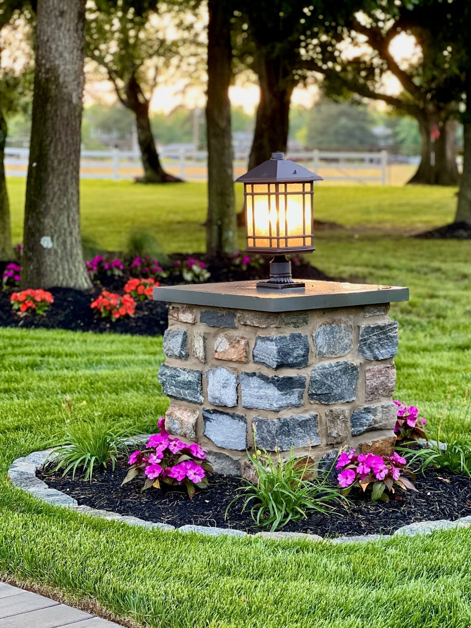 Single stone pillar with lit craftsman lantern at dusk